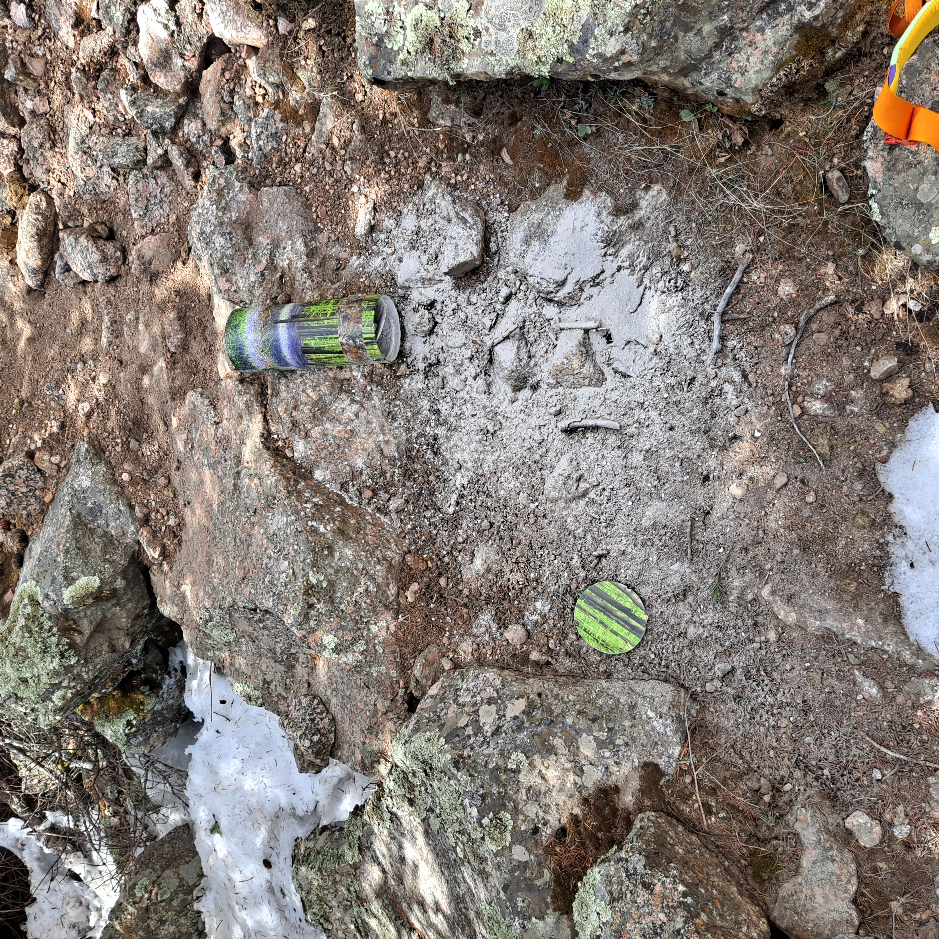 ashes scattered in the dirt and rocks, their container smashed open